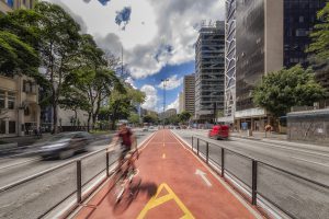 Red, protected bicycle lane in the middle of a six lane inner city road.